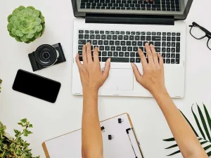 Une personne rédige un texte sur un ordinateur portable, vue de dessus