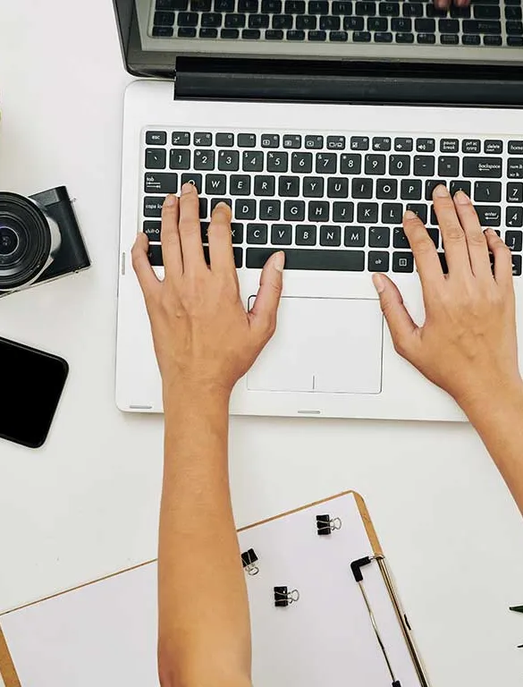 Une personne rédige un texte sur un ordinateur portable, vue de dessus